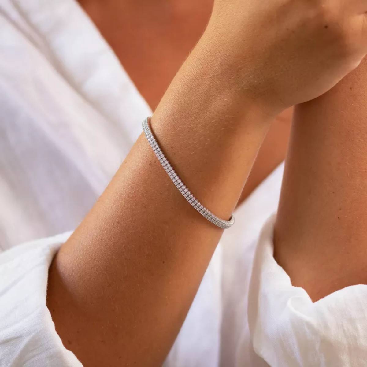 Gros plan sur un bracelet tennis en diamant scintillant porté au poignet d’une femme, symbole d’élégance intemporelle et de raffinement moderne.